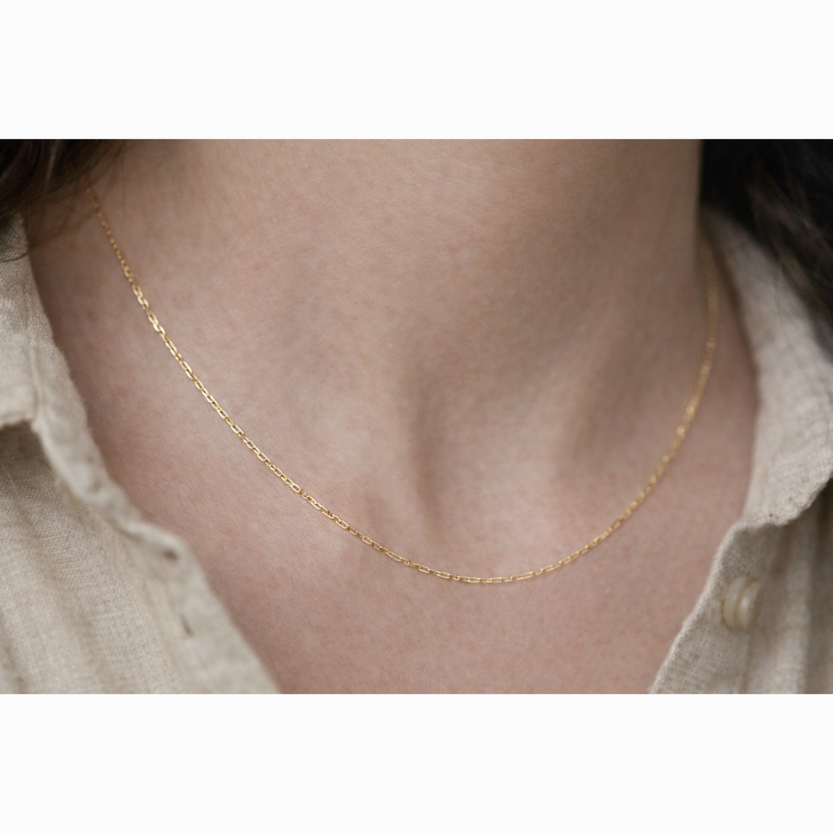 Kabel schakelketting 0,75 mm 14k goud, close-up gedragen om de hals