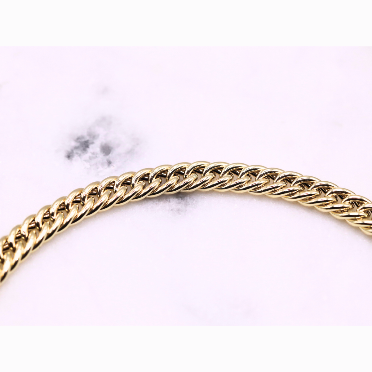 Gourmet armband dubbel 5 mm 14k goud, close-up van de schakels op natuursteen