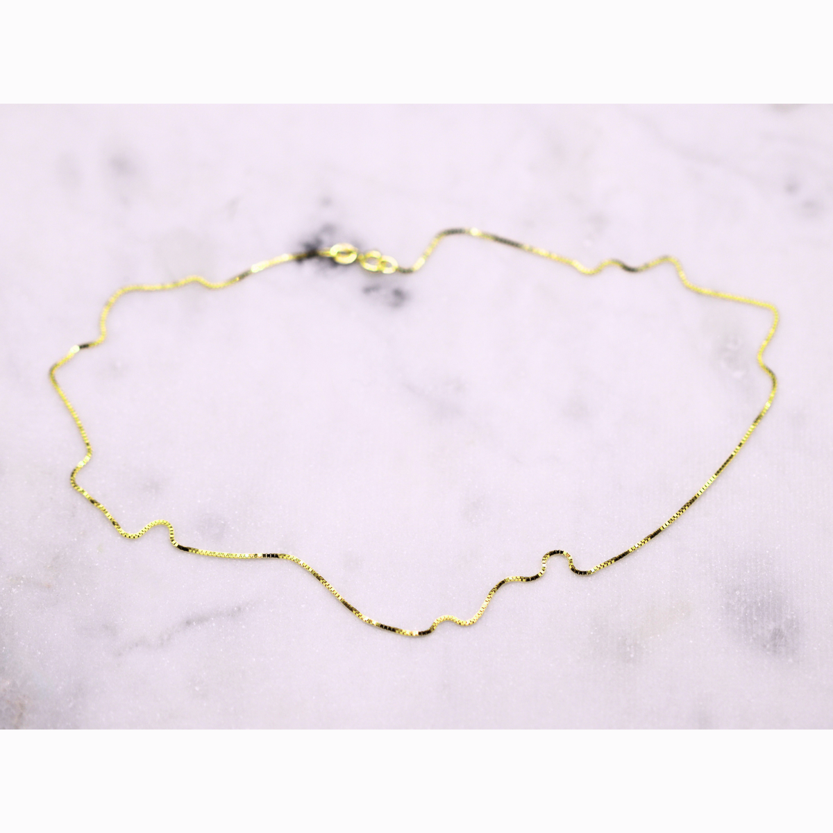Venetiaanse boxketting 0,8 mm 14k goud, opengelegd op natuursteen