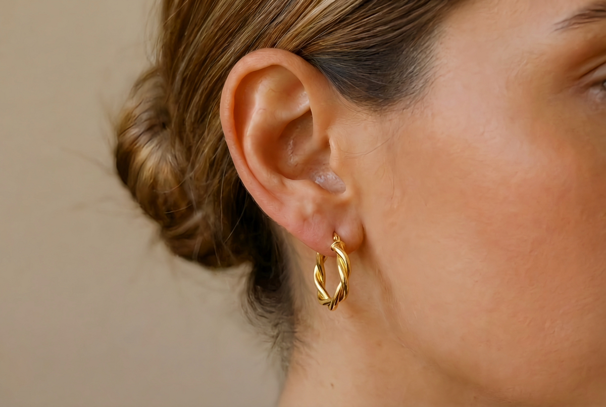 Gevlochten oorringen 18 mm 14k goud, gedragen in het oor