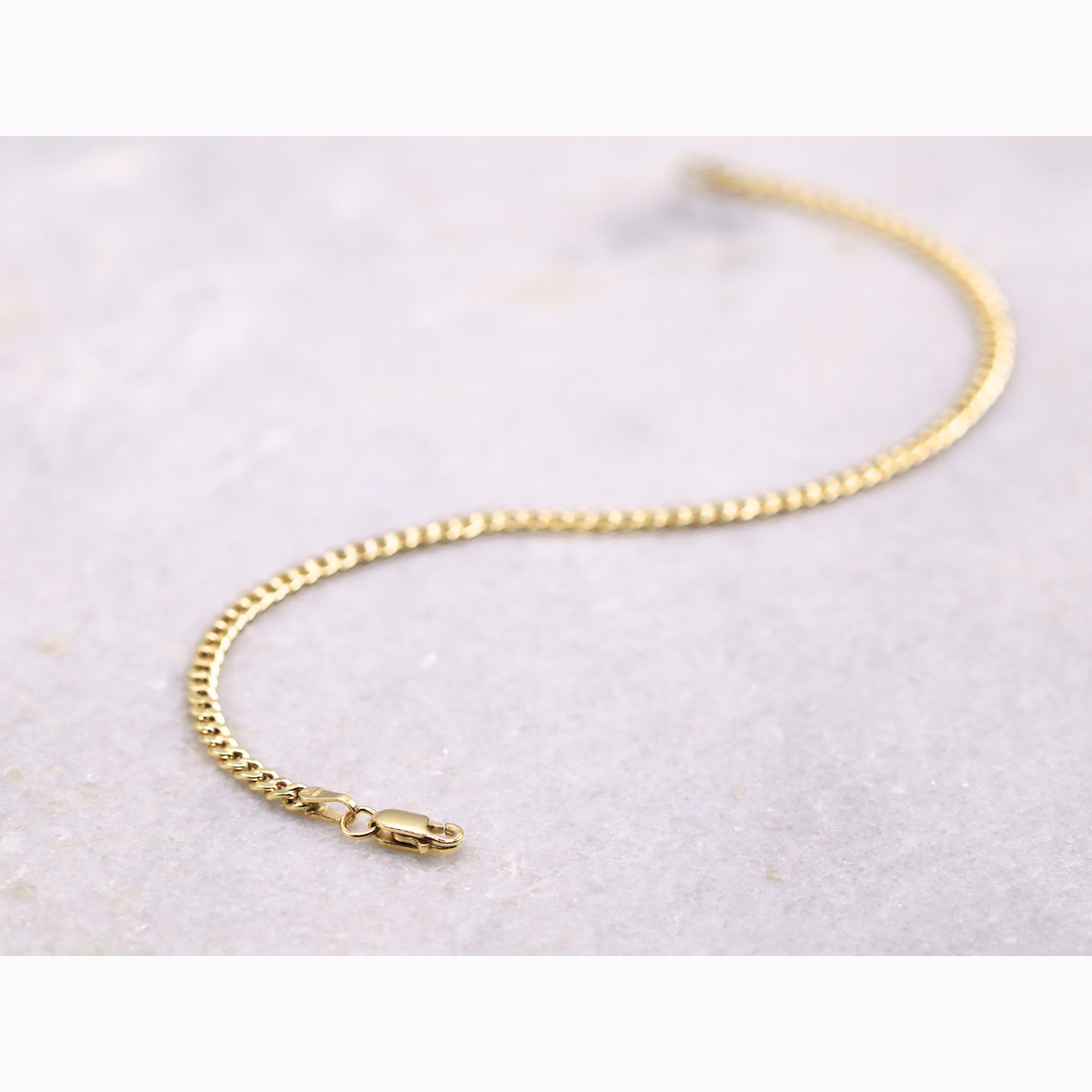 Gourmet armband 2,75 mm 14k goud, S-vormig opengelegd op natuursteen