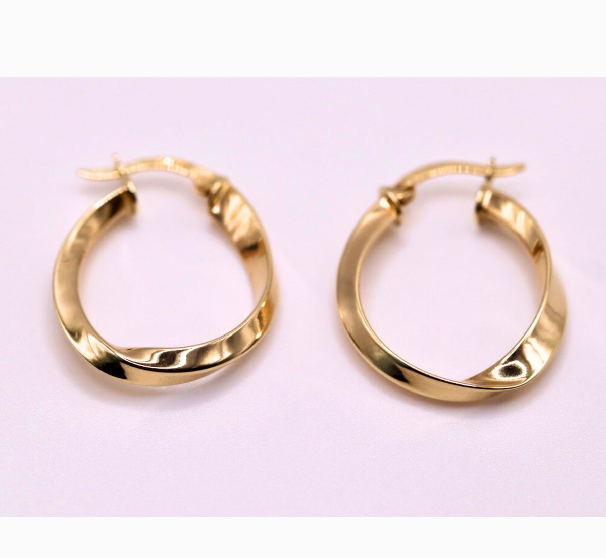 Gedraaide hoepel oorbellen 23 mm 14k goud, paar op lila achtergrond