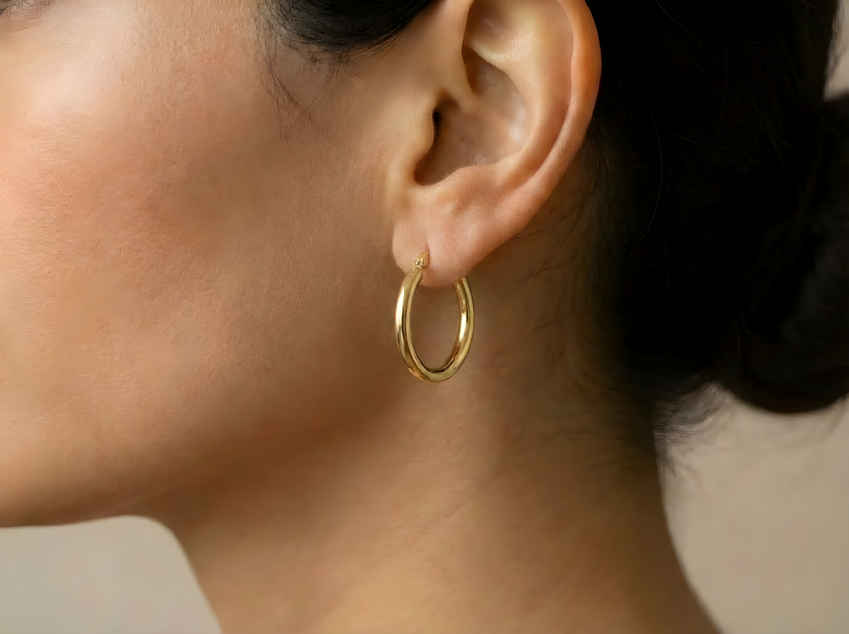 Platte creolen 24 mm 14k goud, gedragen in het oor
