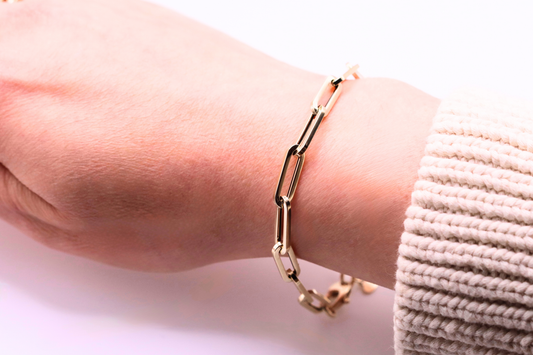 Long Paperclip Schakelarmband 5,5 mm 14k goud, gedragen om de pols