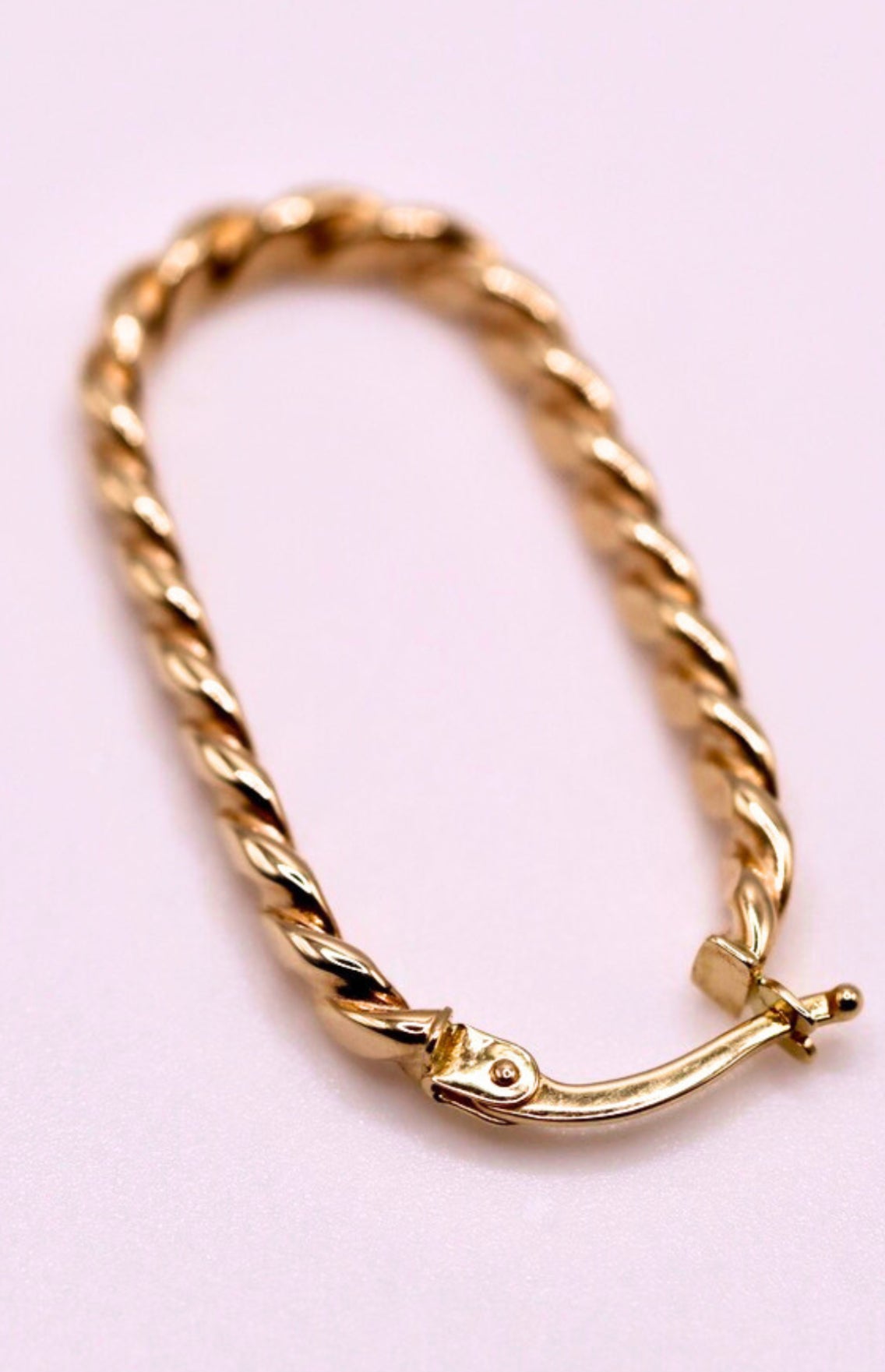 Gedraaide rechthoekcreolen 30 mm 14k goud, close-up op lila achtergrond