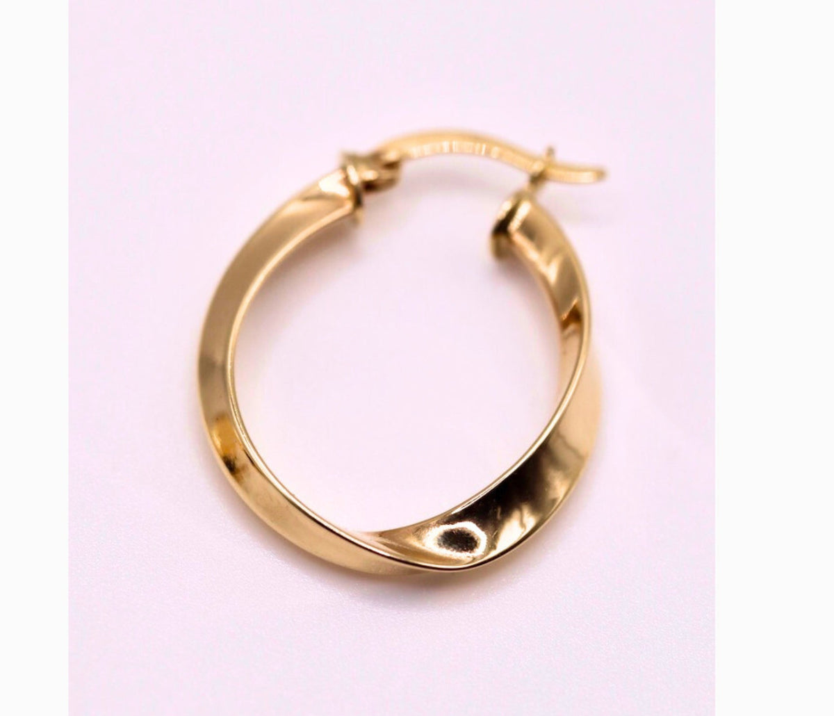 Gedraaide hoepel oorbellen 23 mm 14k goud, close-up op lila achtergrond