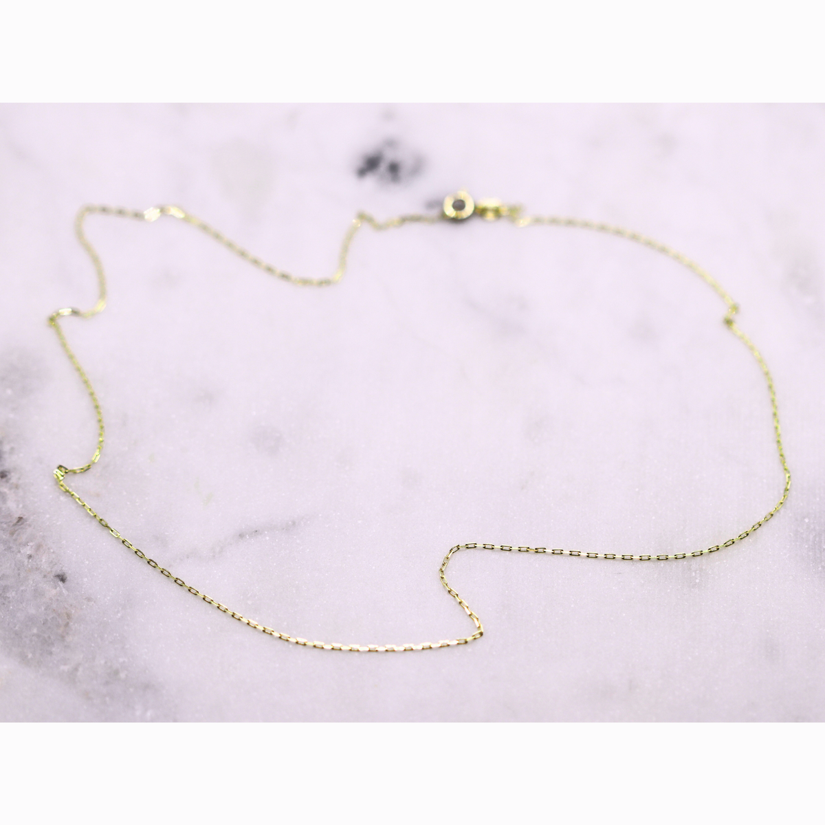 Kabel schakelketting 0,75 mm 14k goud, opengelegd op natuursteen