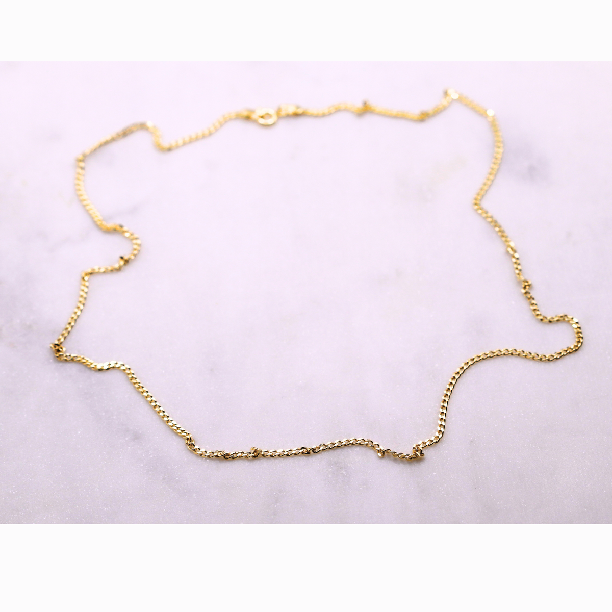 Gourmet ketting 2 mm 14k goud, opengelegd op natuursteen