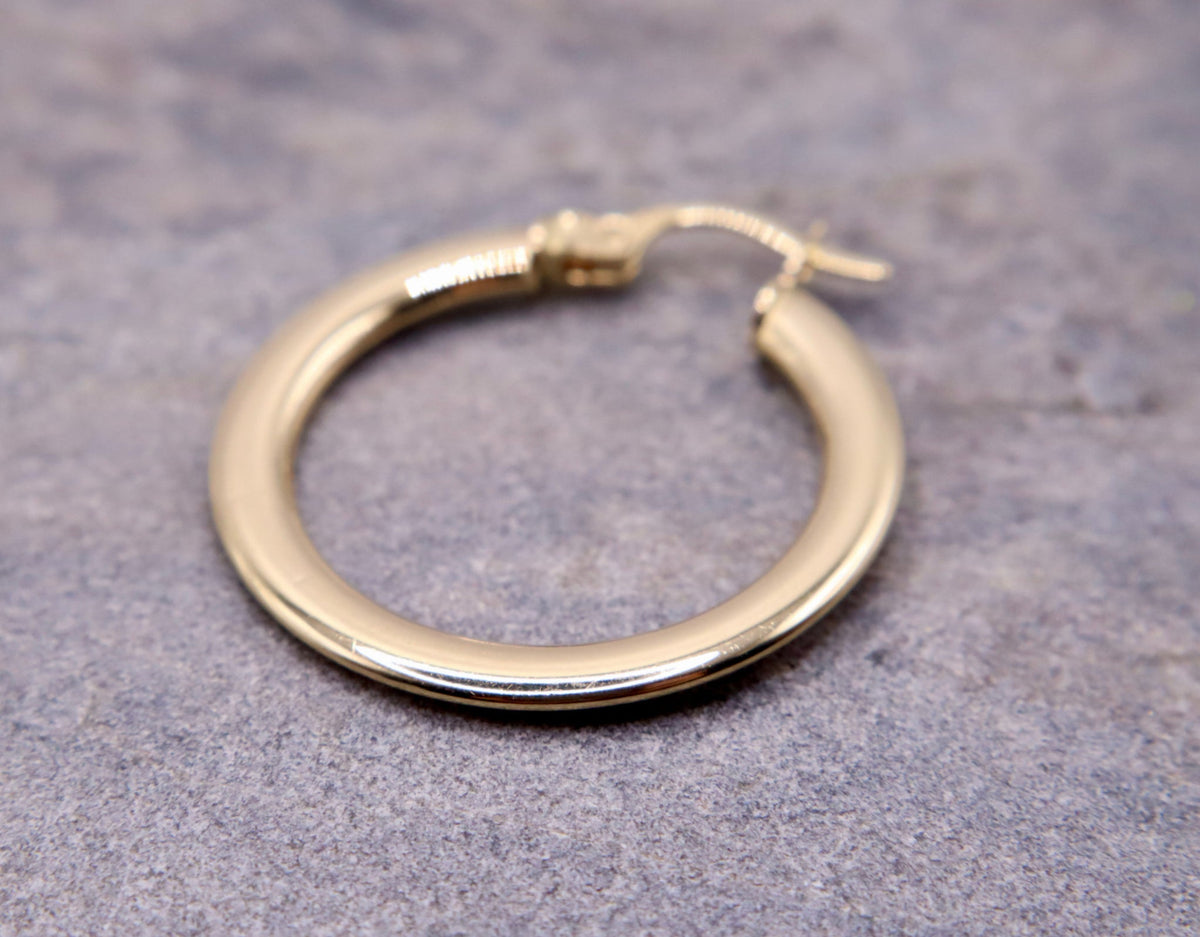 Platte creolen 24 mm 14k goud, close-up op natuursteen