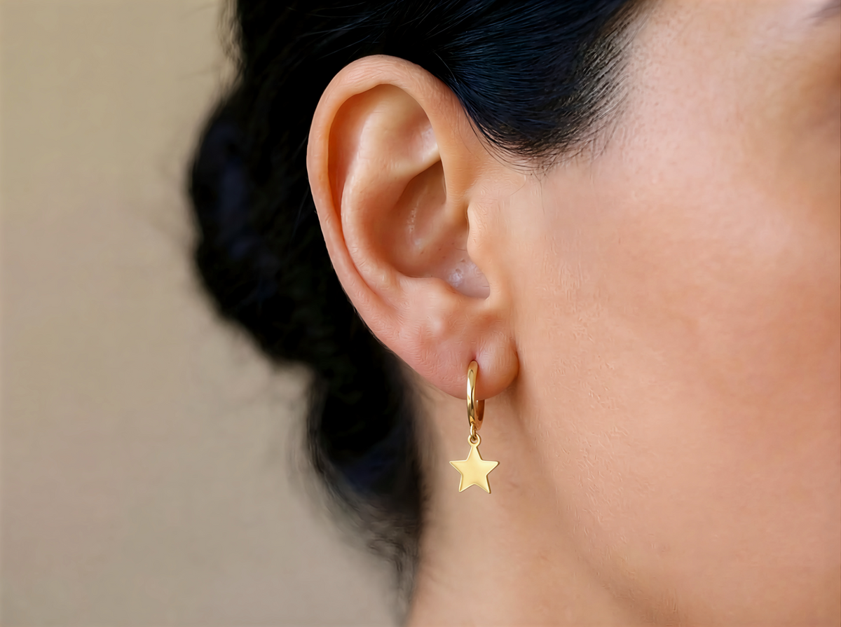 Creolen met sterbedel 12,5 mm 14k goud, gedragen in het oor