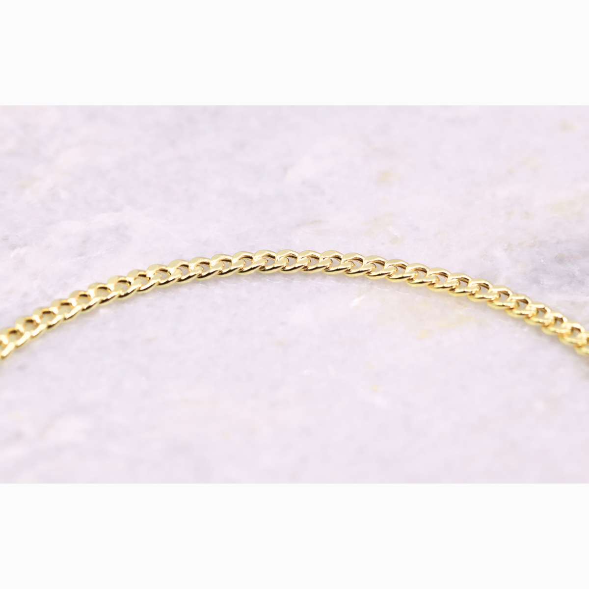 Gourmet armband 2,75 mm 14k goud, close-up van de schakels op natuursteen