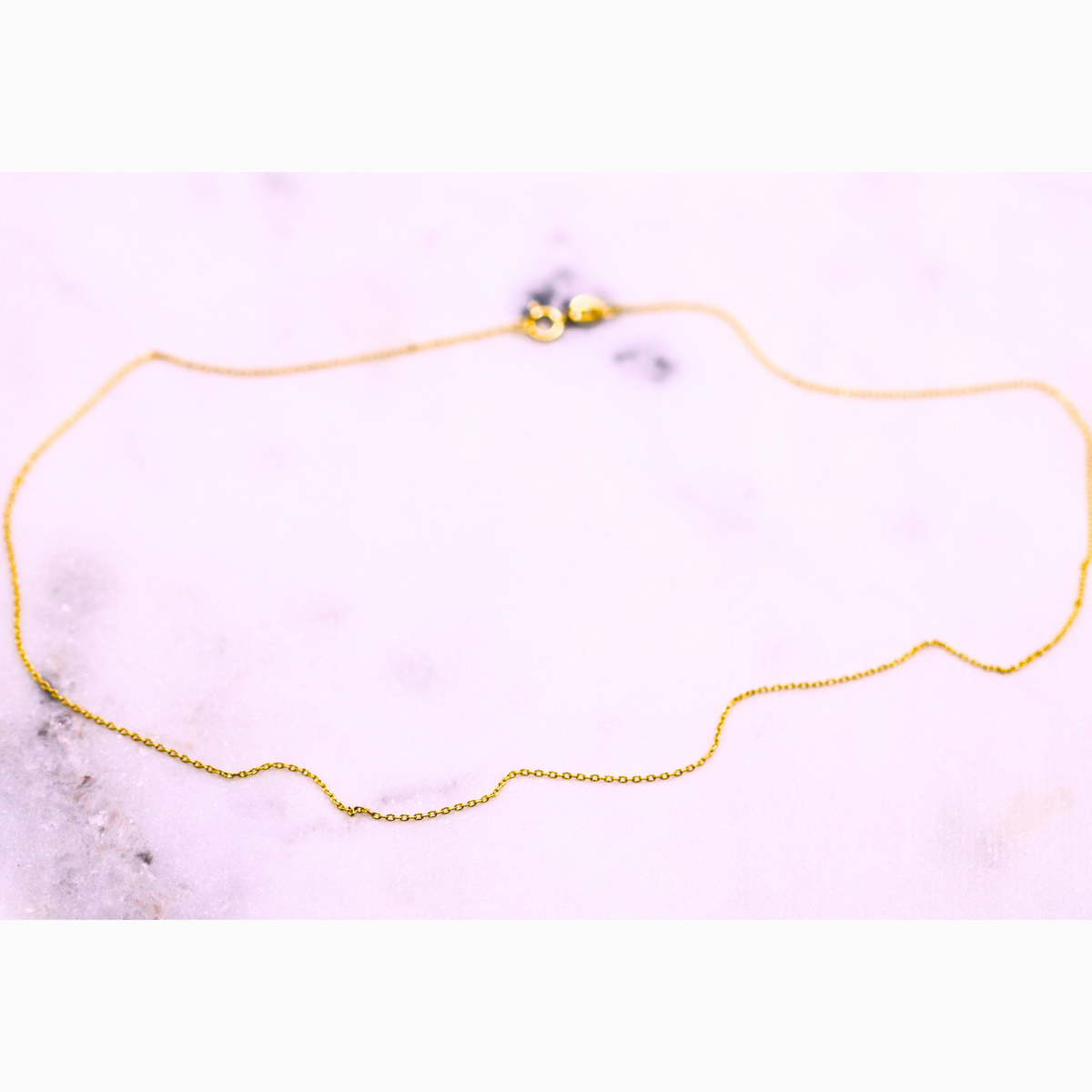 Anker schakelketting 0,6 mm 14k goud, opengelegd op natuursteen