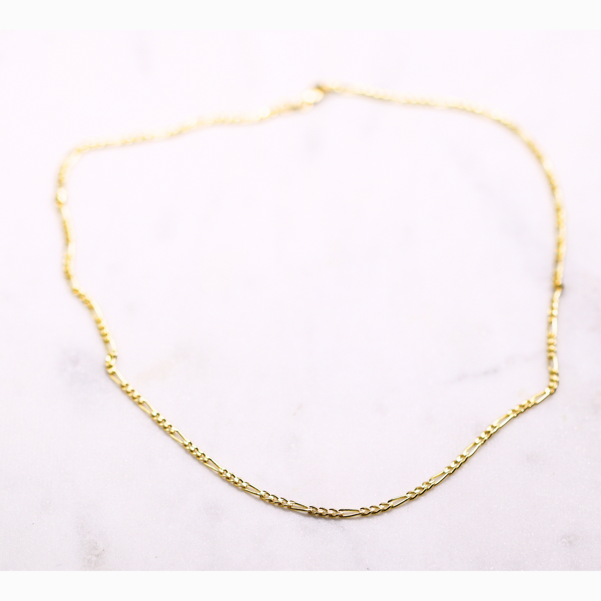 Figaro schakelketting 2,5 mm 14k goud, opengelegd op natuursteen