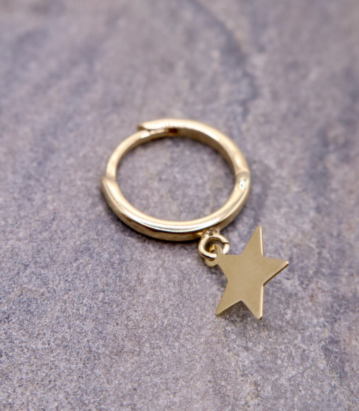 Creolen met sterbedel 12,5 mm 14k goud, close-up op natuursteen