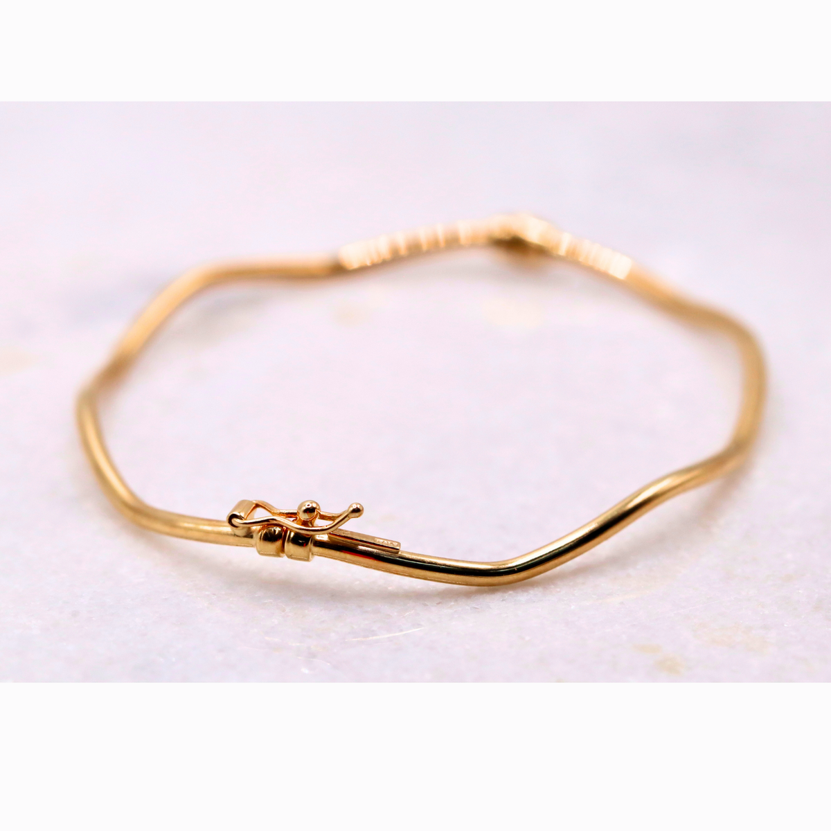 Golvende bangle 2 mm 14k goud, close-up van de open klapsluiting