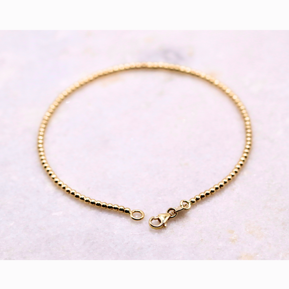 Bolletjes armband 2 mm 14k goud, productfoto in lus met zichtbare sluiting