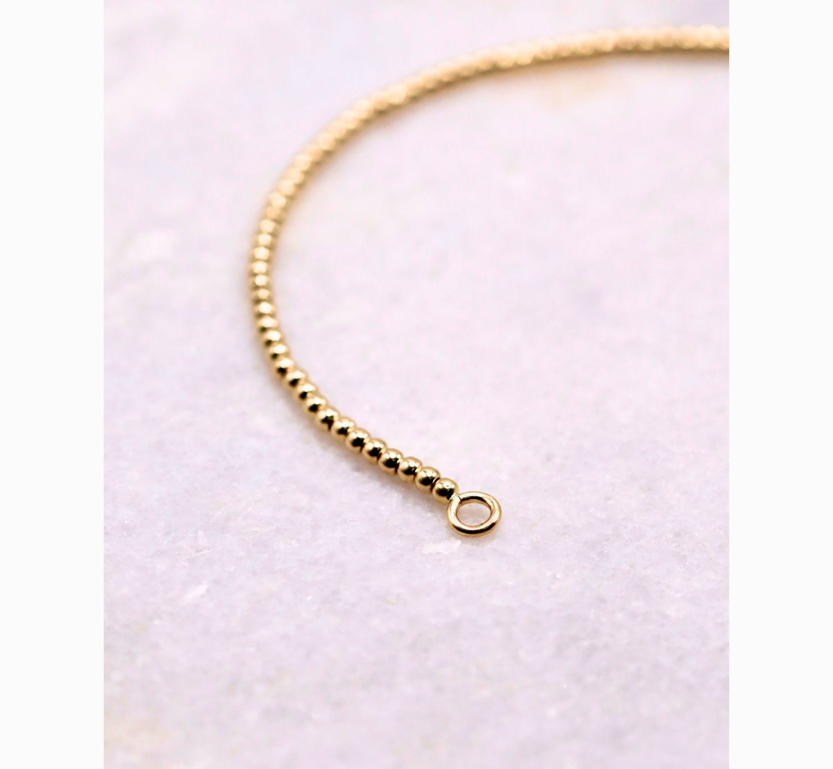 Bolletjes armband 2 mm 14k goud, S-vormig opengelegd op natuursteen