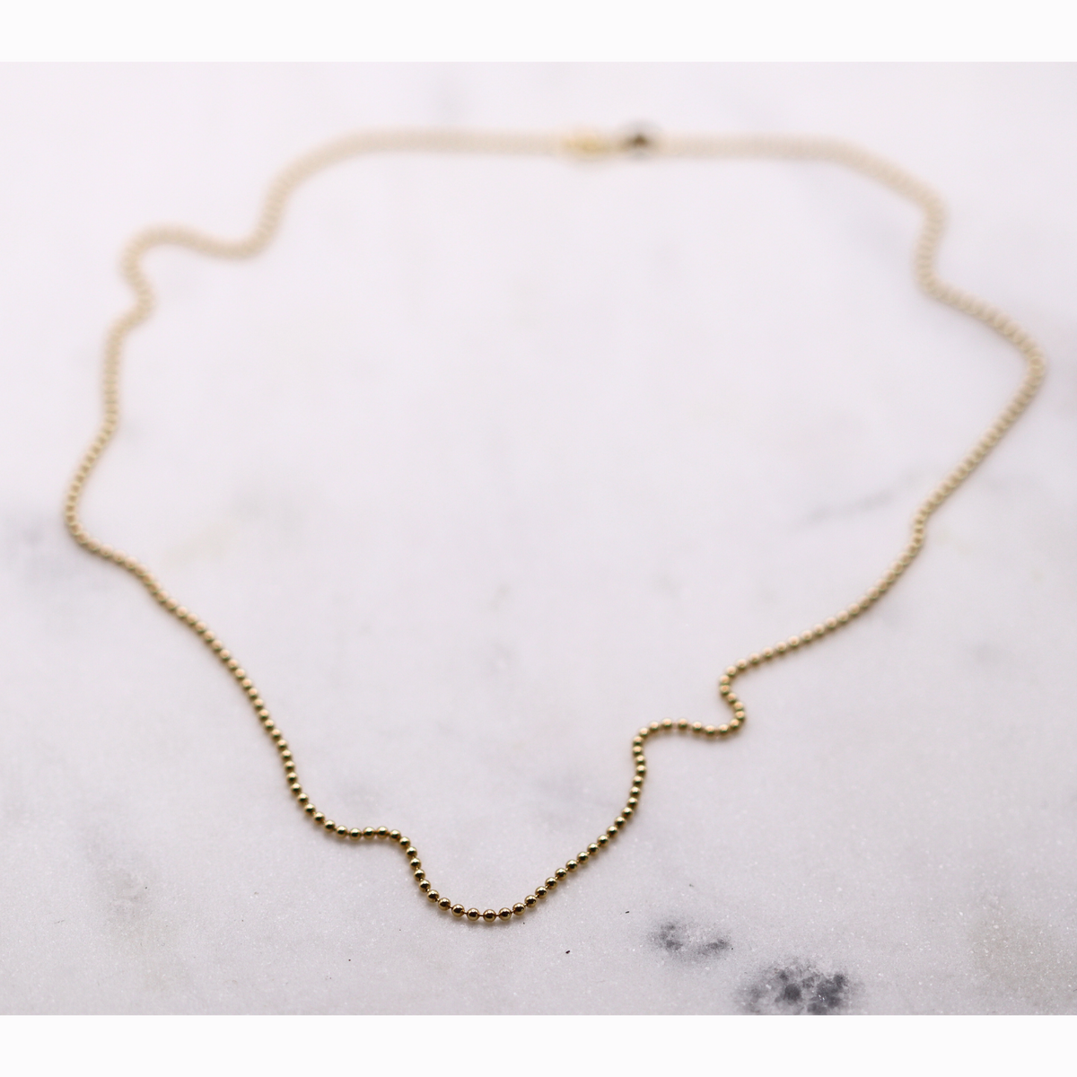 Bolletjesketting 1,5 mm 14k goud, opengelegd op natuursteen
