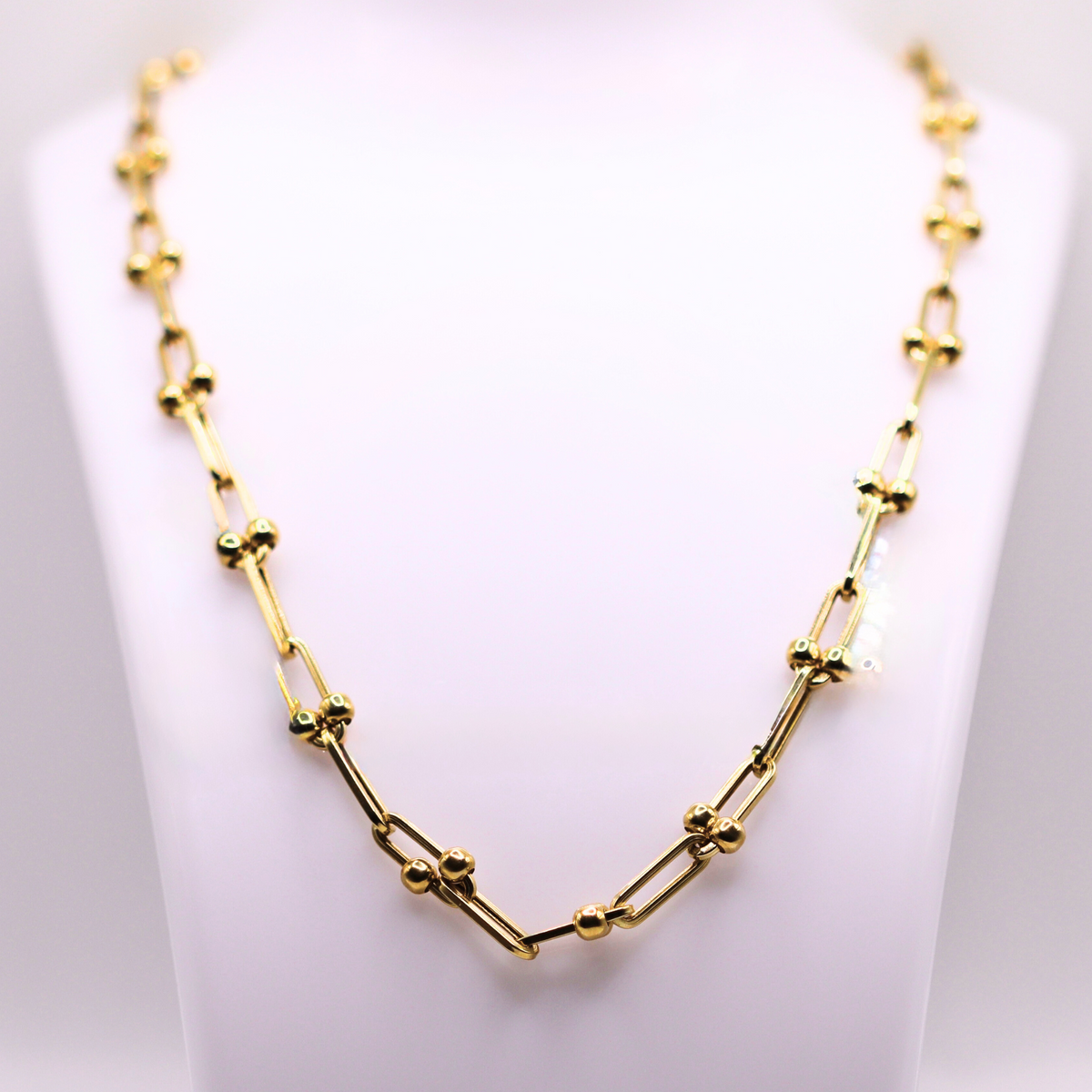Bolletjes schakelketting 5 mm 14k goud op een sieradenbuste