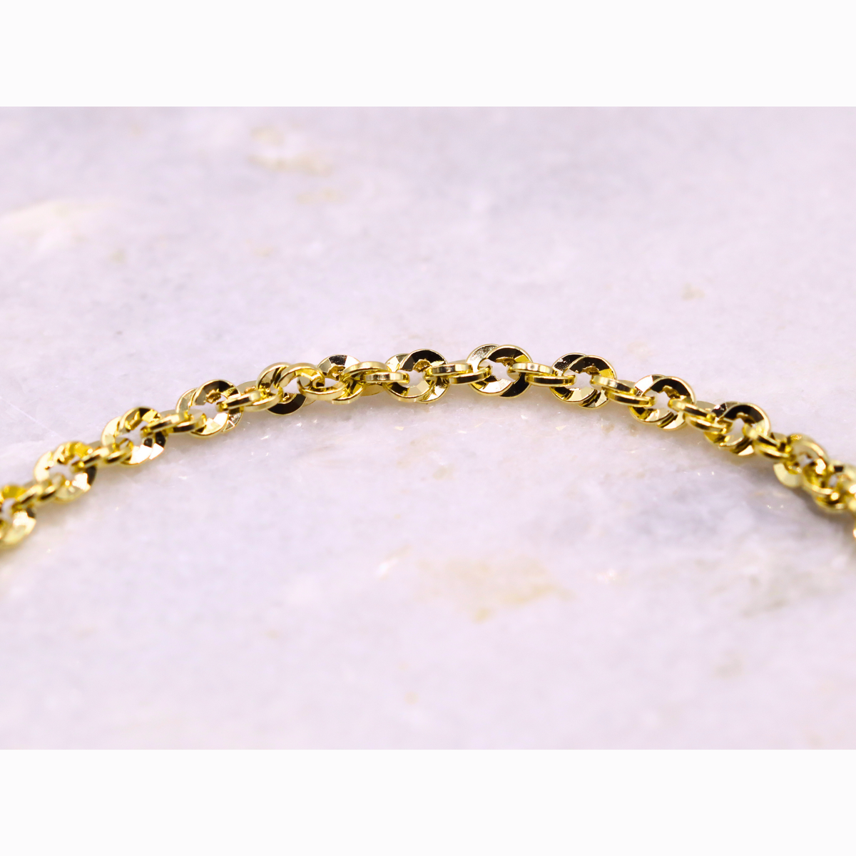 Gedraaide Schakelarmband 4 mm 14k goud, close-up van de gedraaide schakels op steen
