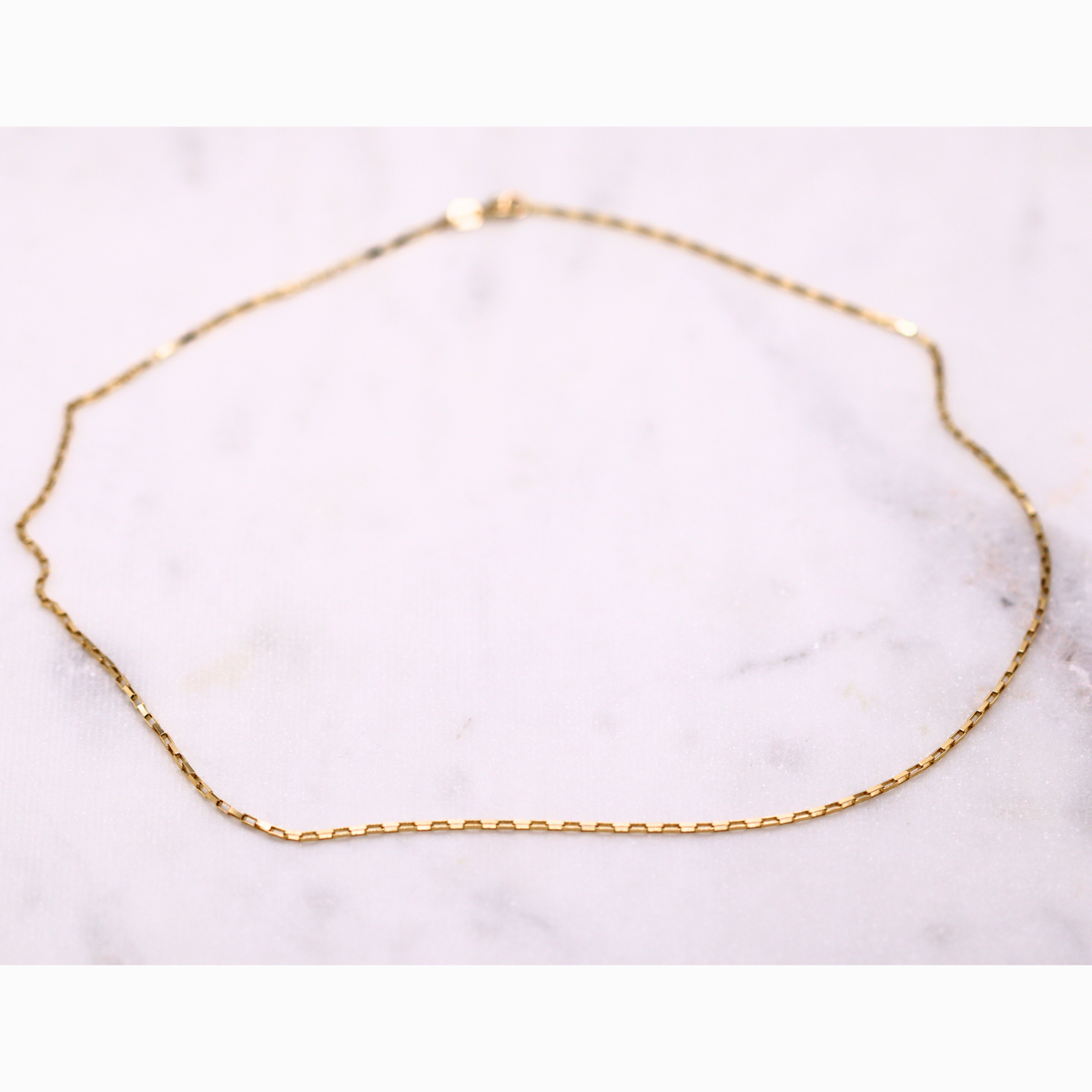 Boxketting 1,25 mm 14k goud, opengelegd op natuursteen