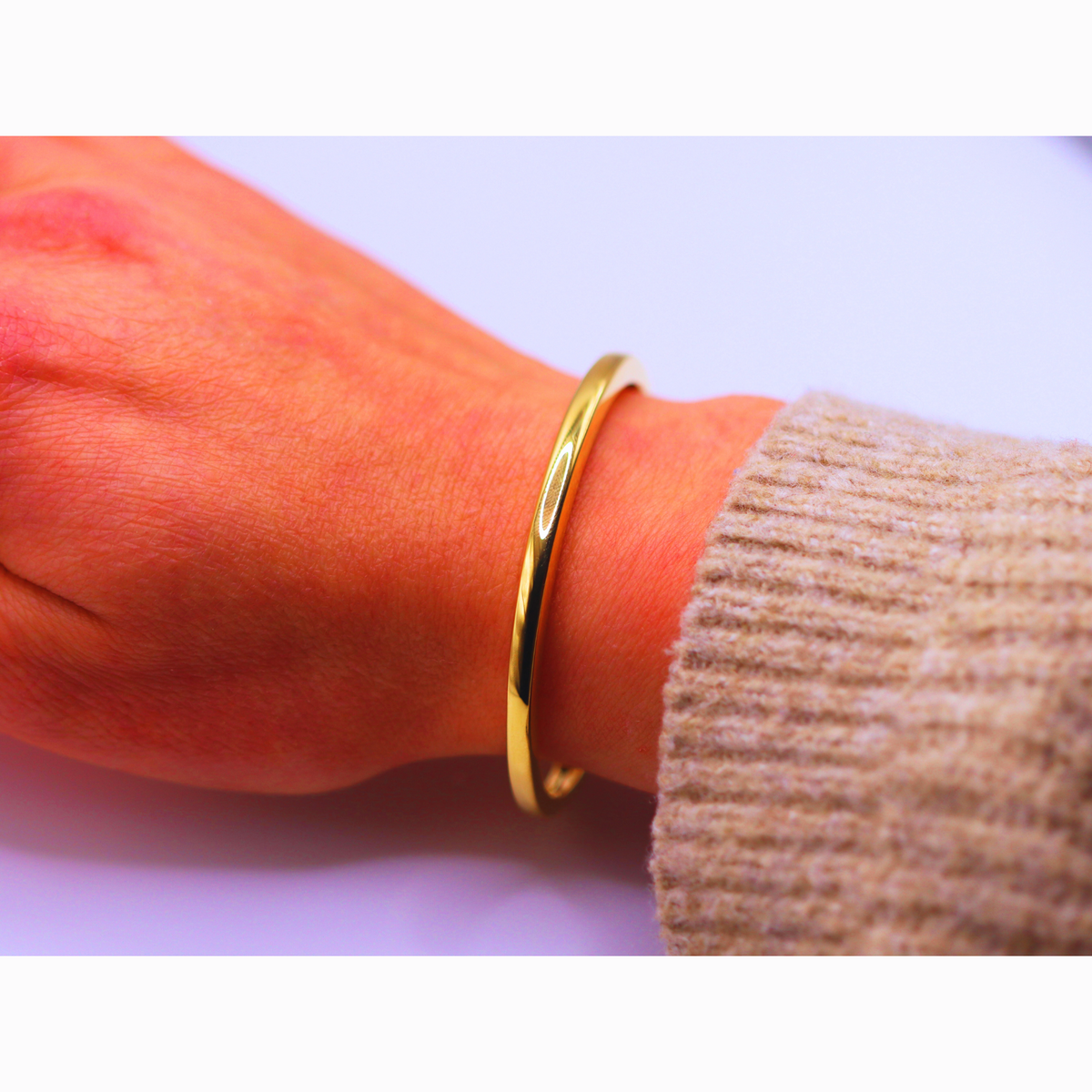 Open bangle 3,75 mm 14k goud, gedragen om de pols bij een beige mouw