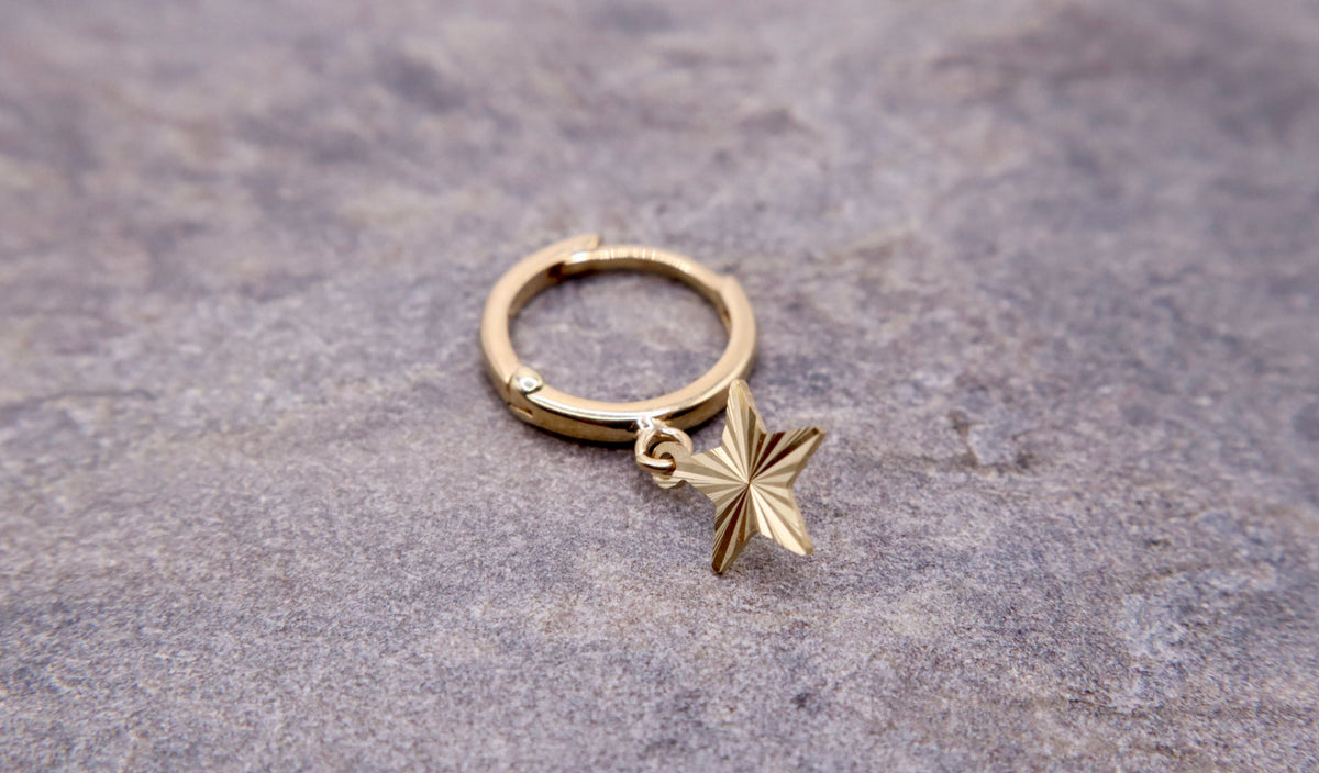 Ster-drop oorbellen 14k goud, close-up op natuursteen