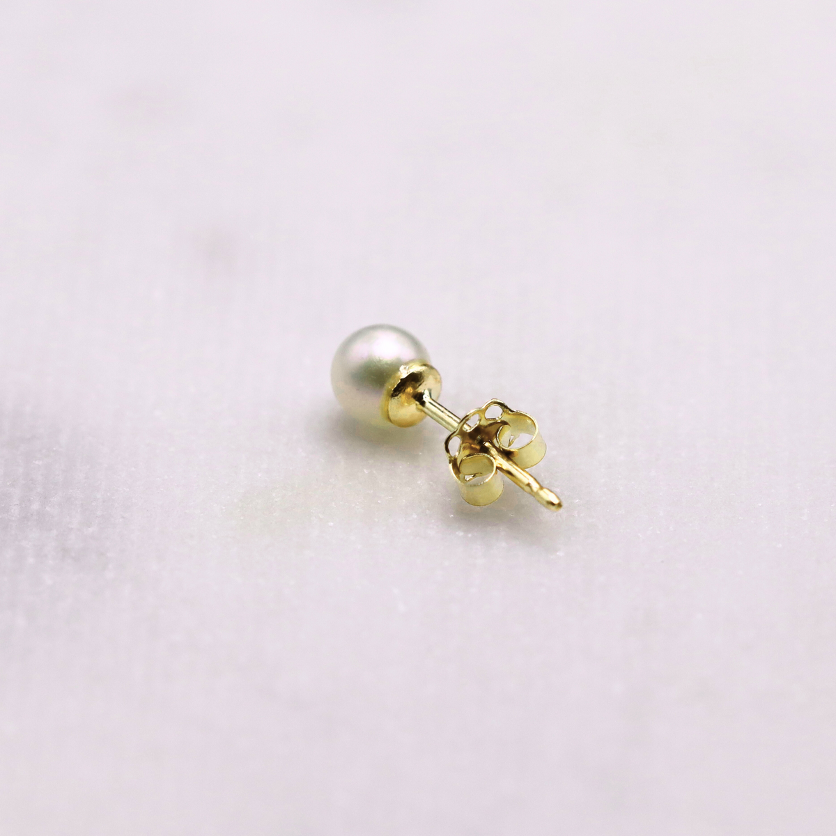 Parel oorstekers 5 mm 14k goud, close-up op natuursteen