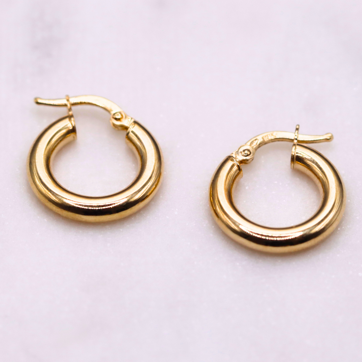 Gladde creolen 16 mm 14k goud, paar opengelegd op natuursteen