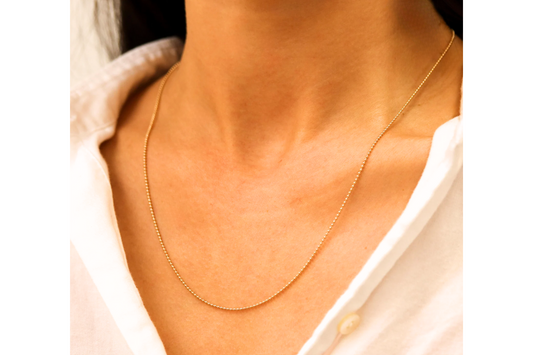 Bolletjesketting 1,5 mm 14k goud, gedragen om de hals door een model