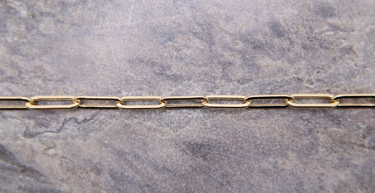 Paperclip Armband Elegance 4 mm 14k goud, close-up van de schakels op natuursteen
