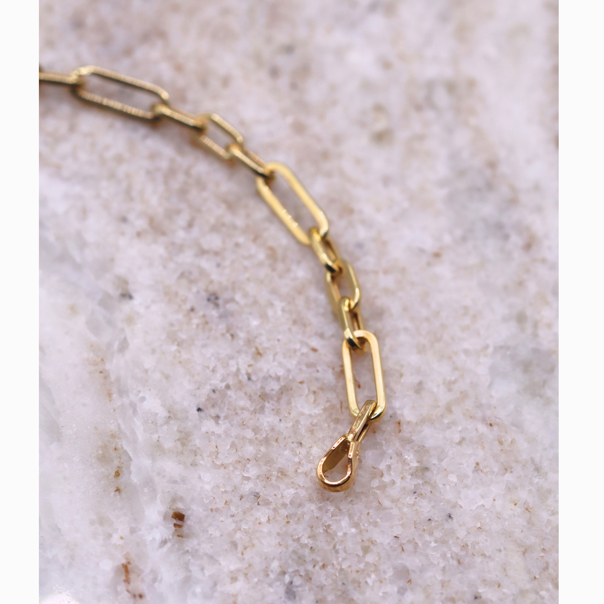 Paperclip armband classic 4 mm 14k goud, close-up van de schakels op natuursteen