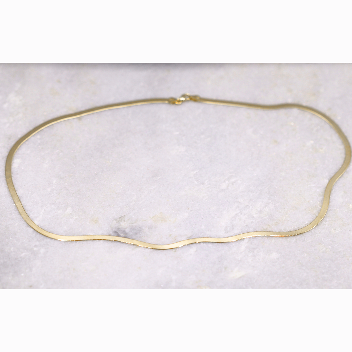 Herringbone ketting 3 mm 14k goud, opengelegd op natuursteen
