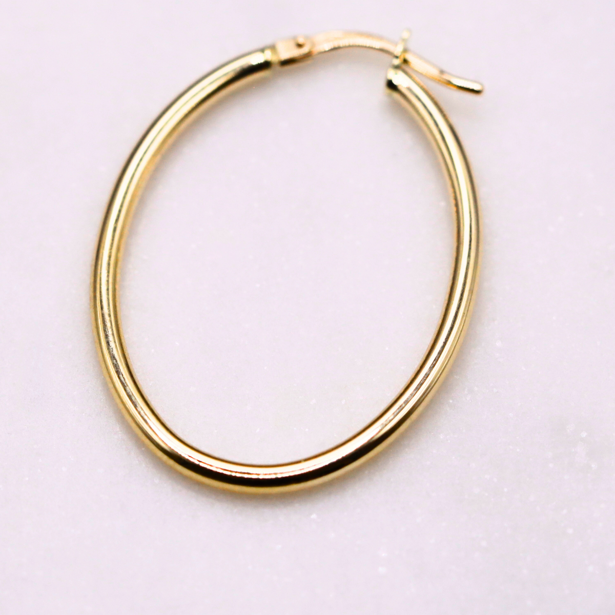 Ovale creolen 33 mm 14k goud, close-up op natuursteen