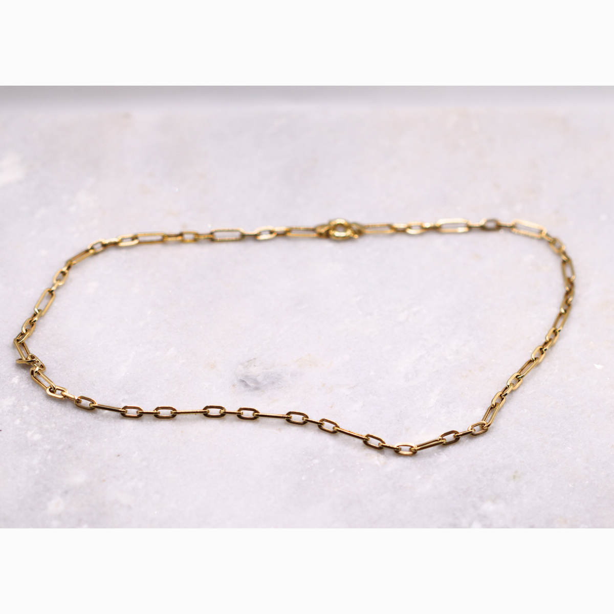 Paperclip ketting 4,5 mm 14k goud, opengelegd op natuursteen