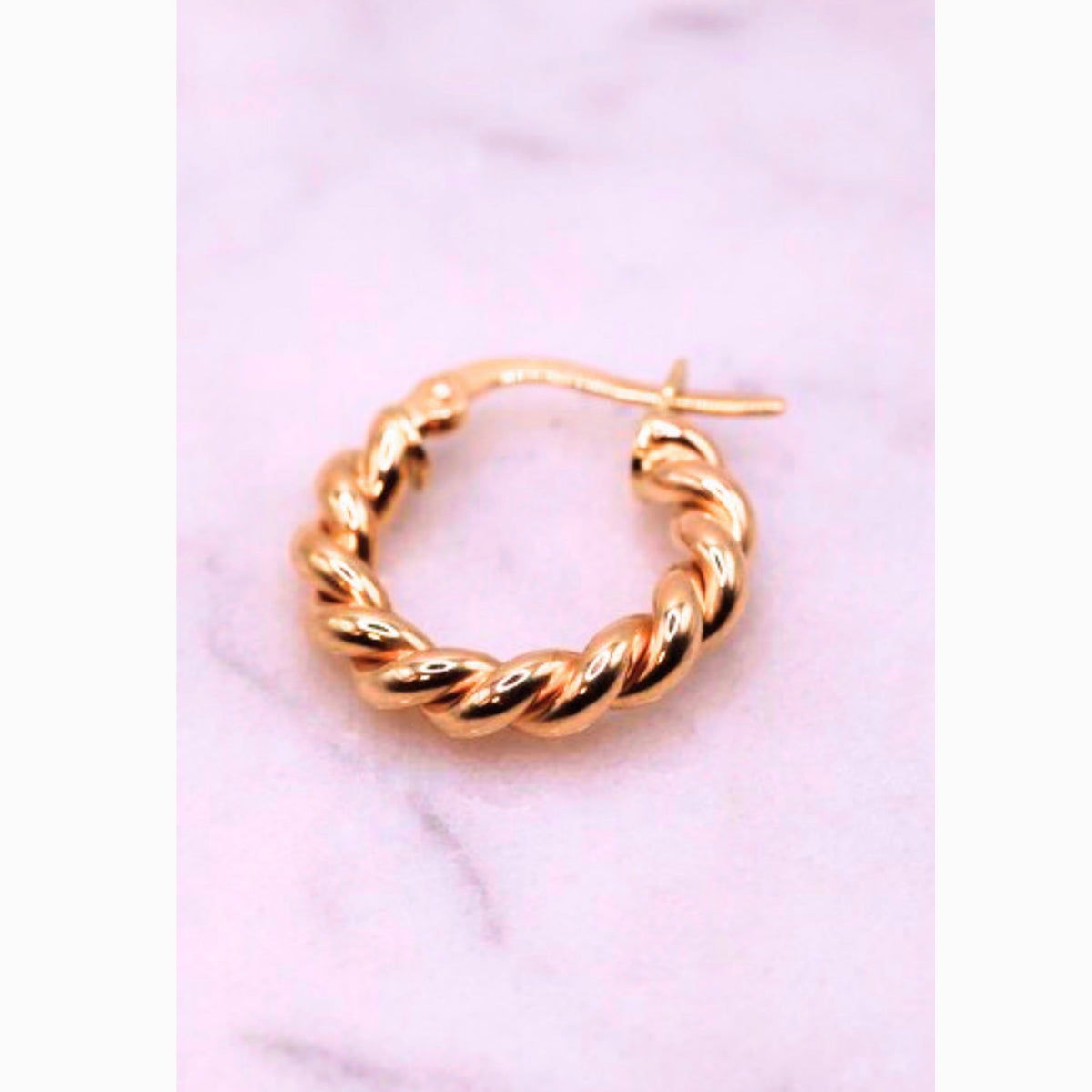 Gevlochten creolen 18 mm 14k goud, close-up op lila achtergrond