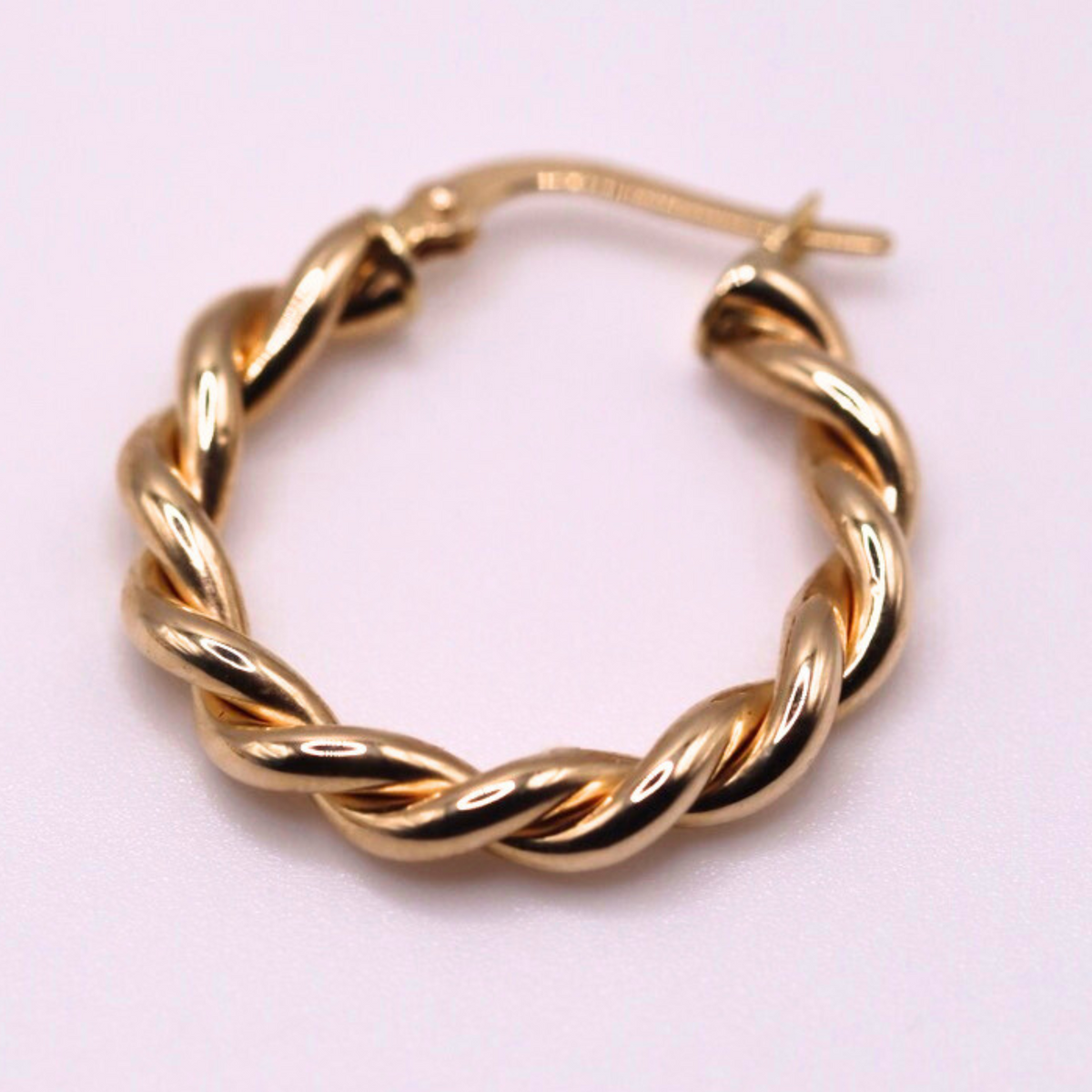 Gedraaide oorringen 22 mm 14k goud, close-up op lila achtergrond
