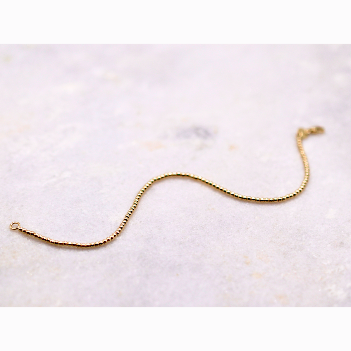 Bolletjes armband 2 mm 14k goud, opengelegd op natuursteen