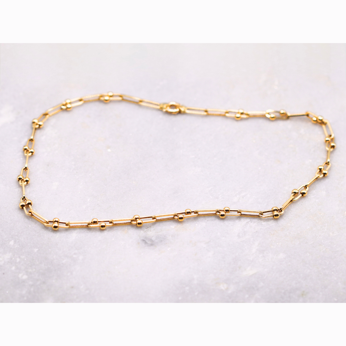 Bolletjes schakelketting 5 mm 14k goud, opengelegd op natuursteen