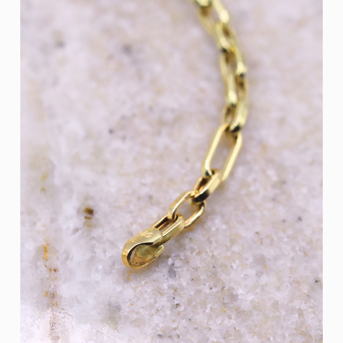 Anker schakelarmband 3 mm 14k goud, close-up van de schakels op natuursteen