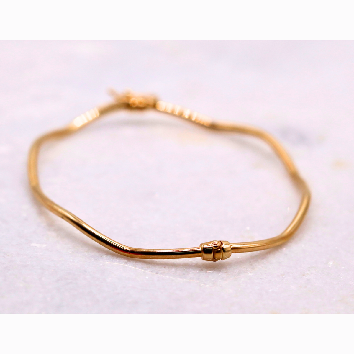 Golvende bangle 2 mm 14k goud, schuin aanzicht met scharnier tegenover de sluiting