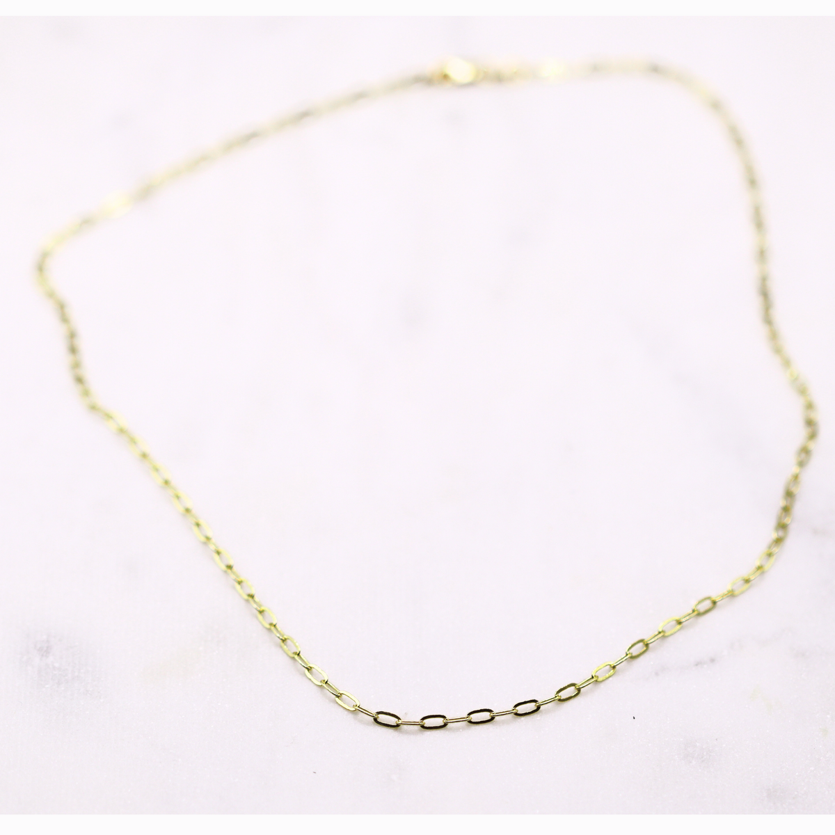 Ovale Schakelketting 2,5 mm 14k goud, opengelegd op natuursteen